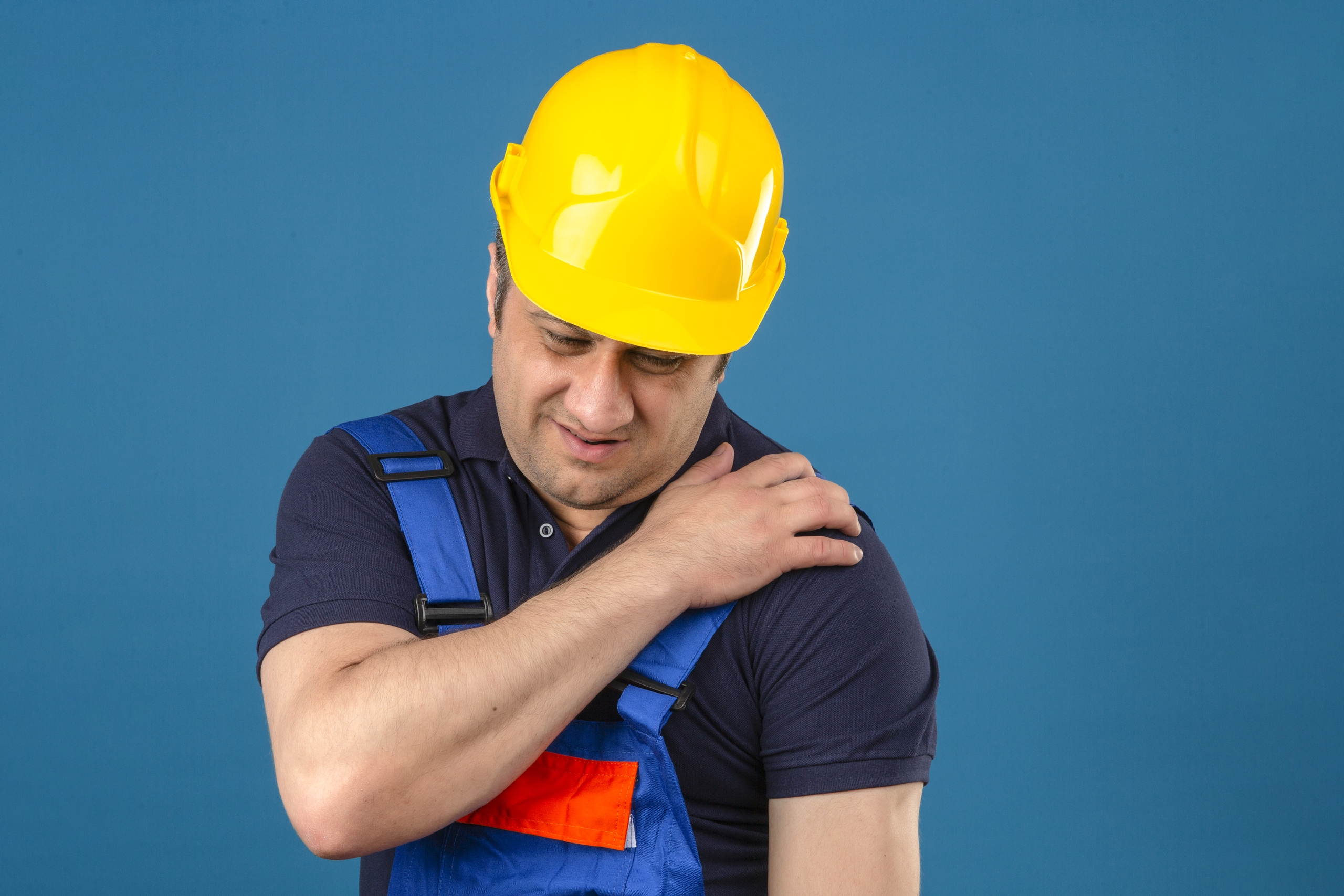 constructor middle aged man wearing construction uniform and safety helmet touching shoulder having pain over isolated blue background