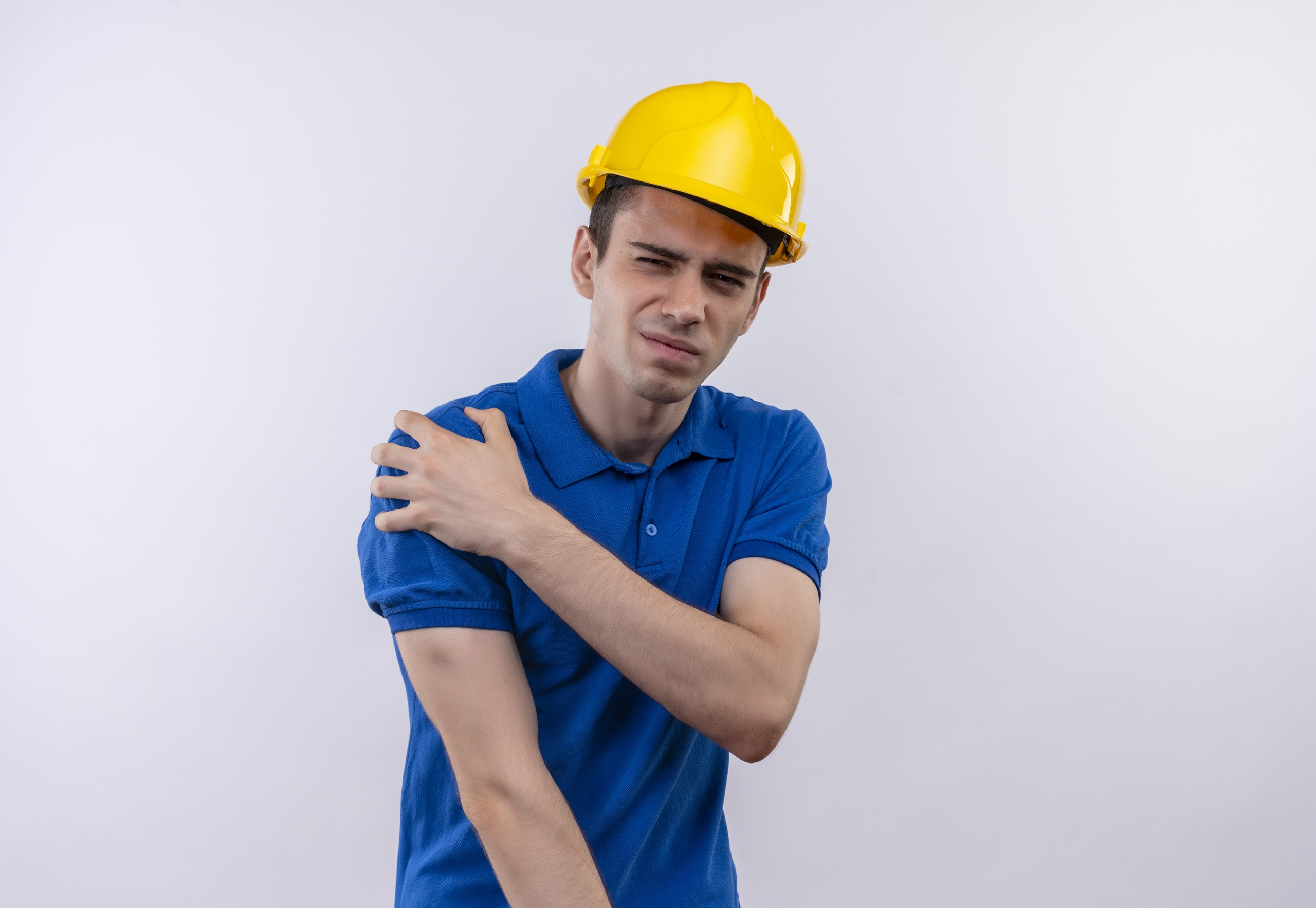 young builder man wearing construction uniform and safety helmet doing unhappy face and suffers from pain over white isolated background