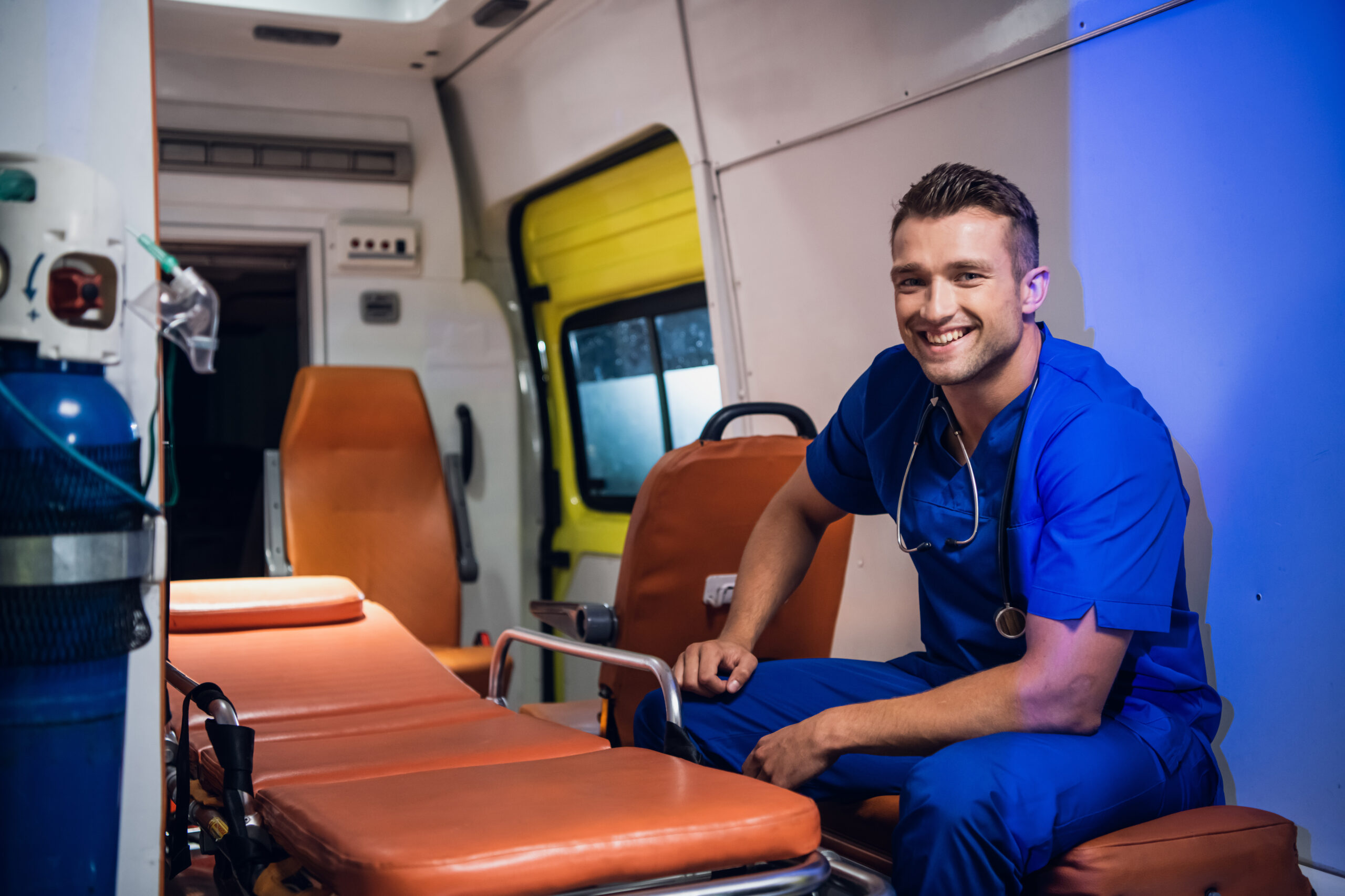 Young positive paramedic in a blue uniform on duty.